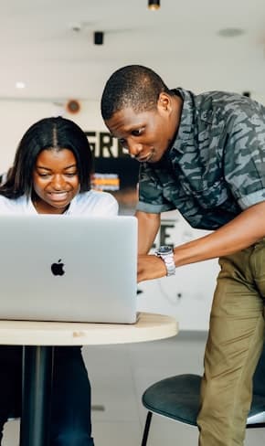 Two colleagues reviewing work together on a laptop