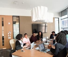 A team meeting around a conference table with laptops open
